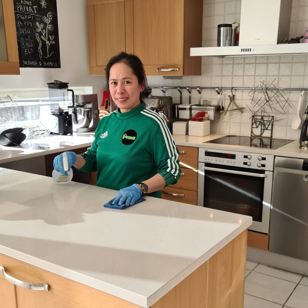 Prime Cleaning team member wiping a kitchen counter during a home visit