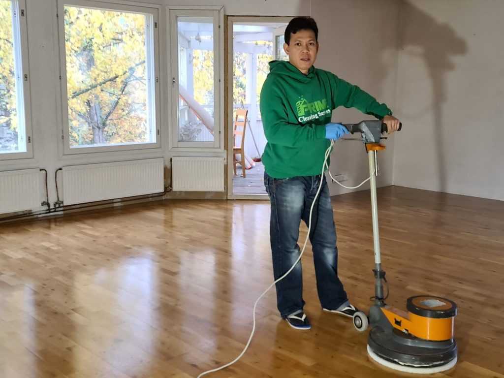 Prime Cleaning team member using a floor polisher in a bright Helsinki apartment