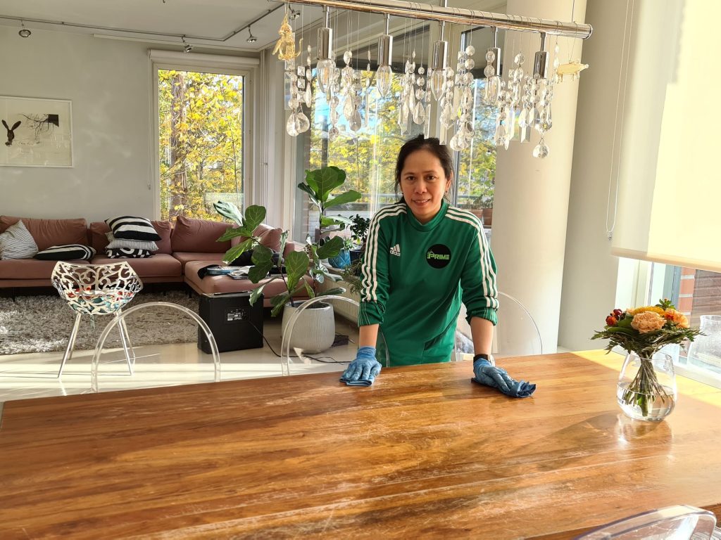 Prime Cleaning team member at a polished dining table in a bright Helsinki living room
